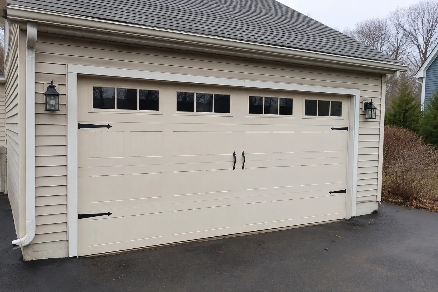 Cream carriage-house-style garage door with dark decorative hardware. — Carriage-House Garage Door Installation, Niagara Falls